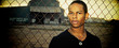 Portrait of young man standing beside steel fence