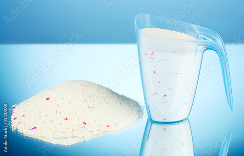 Photo: washing powder in a measuring cup, on blue background close-up washing powder in a measuring cup, on blue background close-up