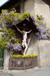 Kreuz Inri Blumen geschmückt lila violett Haus Hauswand