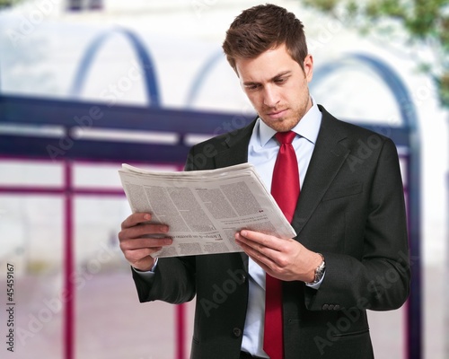 Photo: A businessman reads the finance newspaper while waiting for bus A businessman reads the finance newspaper while waiting for bus