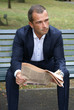 Business with a newspaper, sitting on a park bench