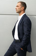 Smartly dressed man posing against a steel wall