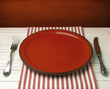 Empty red ceramic plate on white table against red grunge wall