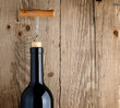 Bottle of wine with corkscrew on wooden background
