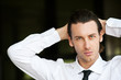 Confident young businessman looking at camera. Dark background.