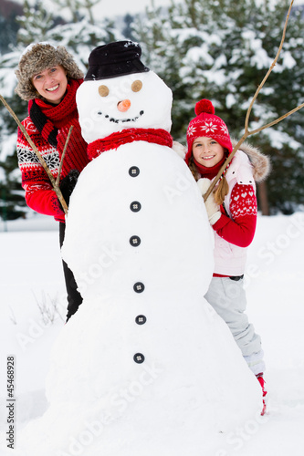 Photo: Winter fun, snowman and happy family Winter fun, snowman and happy family