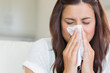 Brunette blowing nose into tissue