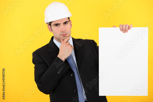 Photo: A pensive architect holding a poster. A pensive architect holding a poster.