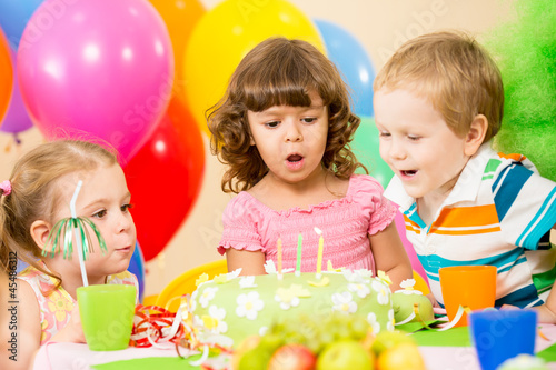 Photo: kids celebrating birthday party and blowing candles on cake kids celebrating birthday party and blowing candles on cake