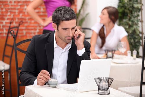 Photo: Man in restaurant with computer and phone Man in restaurant with computer and phone
