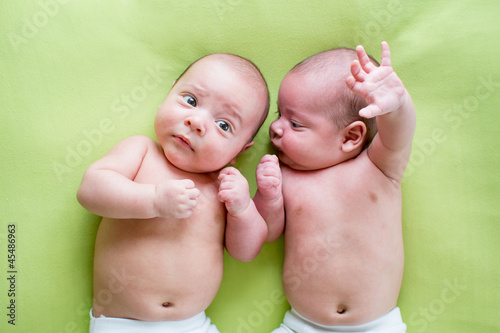 Photo: two twins brothers babies lying on green two twins brothers babies lying on green