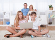 Children On The Carpet Using Tablet And Laptop