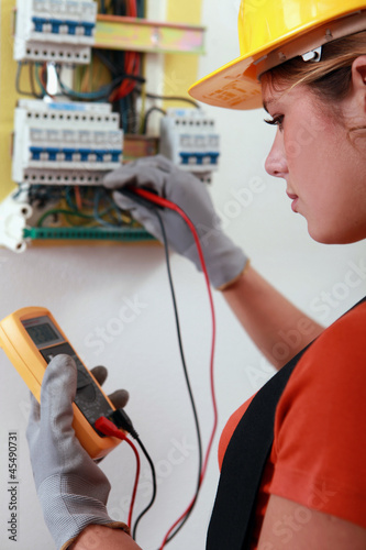 Photo: Female electrician checking the wiring on a fusebox Female electrician checking the wiring on a fusebox