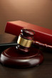 wooden gavel and books on wooden table, on brown background