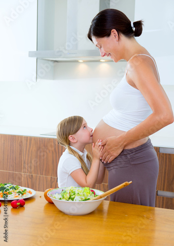 Photo: Beautiful pregnant mother with her daughter at kitchen Beautiful pregnant mother with her daughter at kitchen