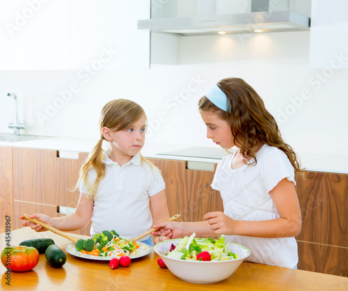 Photo: Beautiful chef sisters at home kitchen preparing salad Beautiful chef sisters at home kitchen preparing salad