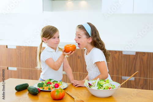 Photo: Beautiful chef sisters at home kitchen preparing salad Beautiful chef sisters at home kitchen preparing salad