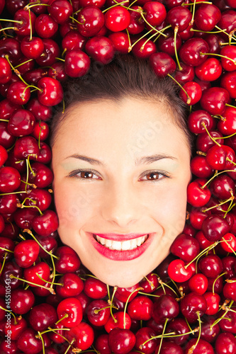 Photo: Young woman smiling face portrait surrounded by cherries. Young woman smiling face portrait surrounded by cherries.