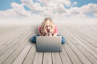 Photo: Pretty girl working on a laptop on a wood floor Pretty girl working on a laptop on a wood floor