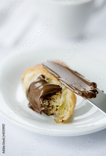 Photo: Chocolate spread on a croissant with a knife Chocolate spread on a croissant with a knife