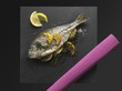 Fried bream with lemons and herbs on a slate plate