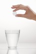 Photo: A hand holding an effervescent tablet over a glass A hand holding an effervescent tablet over a glass