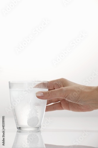Photo: A hand holding a glass with an effervescent tablet A hand holding a glass with an effervescent tablet