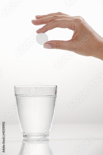 Photo: A hand holding an effervescent tablet over a glass A hand holding an effervescent tablet over a glass