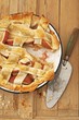 Apple Lattice Crust Pie with Slice Removed; On Wooden Surface with Knife; From Above