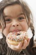 Girl holding a doughnut with sprinkles, partly eaten