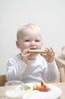 Small boy at breakfast with half a bread roll