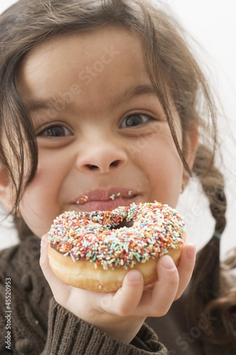 Photo: Girl holding a doughnut with sprinkles, partly eaten Girl holding a doughnut with sprinkles, partly eaten