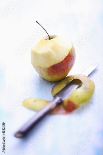 Photo: A half-peeled apple with a knife A half-peeled apple with a knife