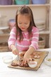 A girl decorating biscuits with icing sugar