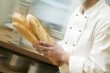 Chef hurrying through kitchen with baguettes