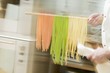 Chef hurrying through kitchen with ribbon pasta on wooden spoon