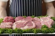 Person holding tray of various cuts of meat