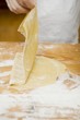 Child lifting up rolled-out pasta dough