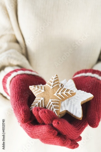 Photo: Hands in woollen gloves holding gingerbread stars Hands in woollen gloves holding gingerbread stars