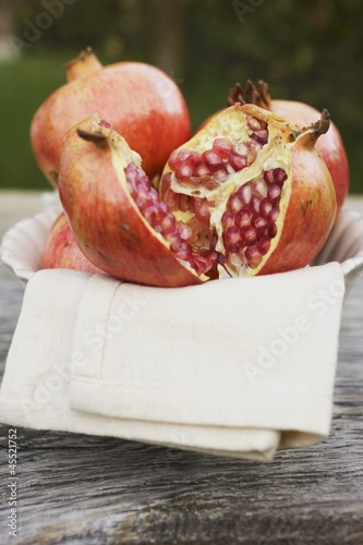 Photo: Pomegranates, whole and halved, on cloth in white bowl Pomegranates, whole and halved, on cloth in white bowl