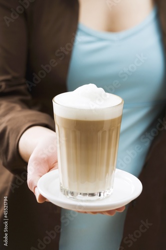 Photo: Woman holding a glass of latte macchiato Woman holding a glass of latte macchiato
