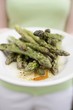 Woman holding a plate of grilled green asparagus