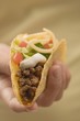 Hand holding taco filled with mince and cheese