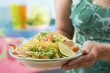 Woman holding plate with two chicken tacos