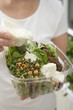 Foto: Woman pouring dressing over salad in plastic container Woman pouring dressing over salad in plastic container