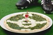 Spinach and mozzarella pizza, football boots in background
