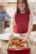 Young woman holding roasted root vegetables in roasting dish