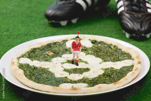 Photo: Spinach and mozzarella pizza, football boots in background Spinach and mozzarella pizza, football boots in background