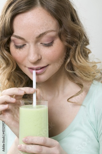Photo: Woman drinking cucumber shake through a straw Woman drinking cucumber shake through a straw