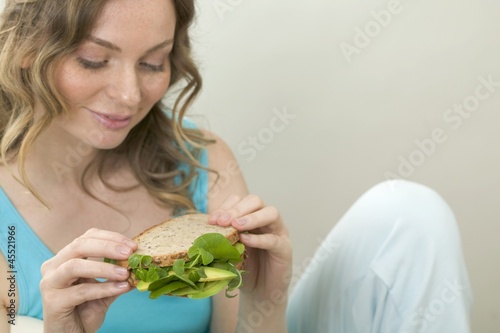 Photo: Woman holding wholemeal avocado and watercress sandwich Woman holding wholemeal avocado and watercress sandwich